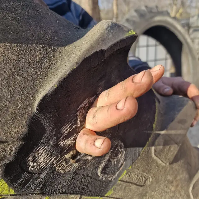 Mână care arată o tăietură adâncă în anvelopa unui utilaj