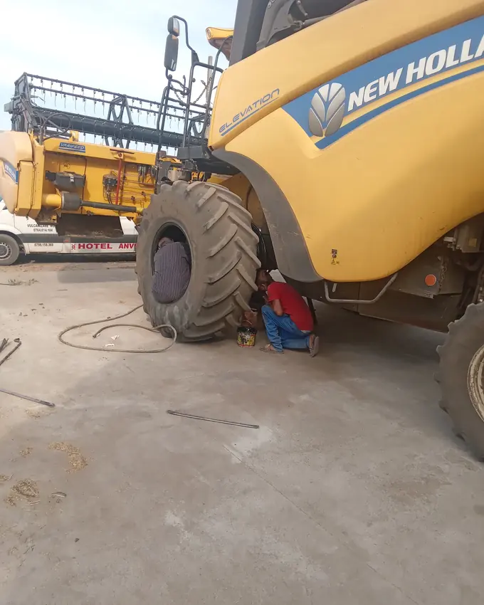 Combină New Holland galbenă cu roata din față demontată